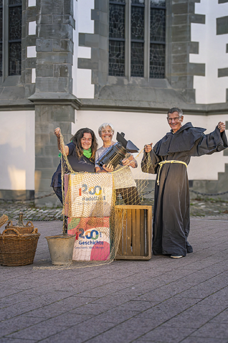 Radolfzell: Menschen feiern 1200 Jahre Geschichte. Mönch, Frauen, Scheinwerfer, Kisten und Requisiten.