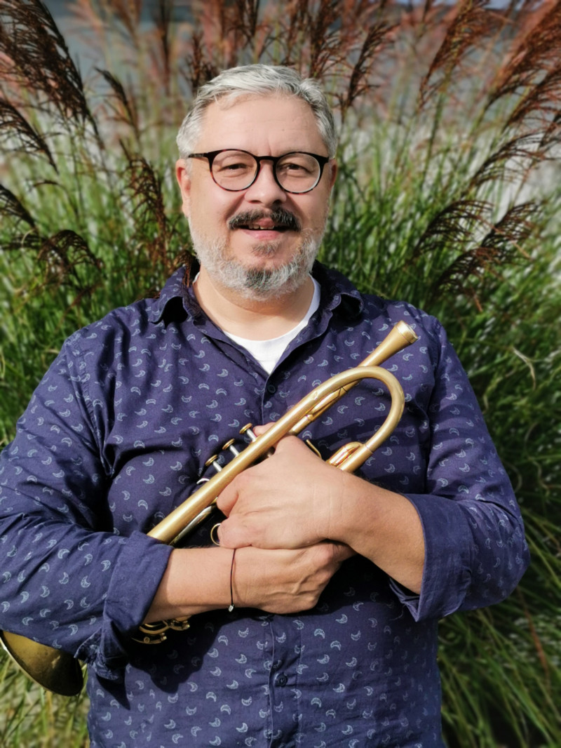 Mann mit Trompete. Musiker mit Brille und Bart vor Gras. Musikinstrument.