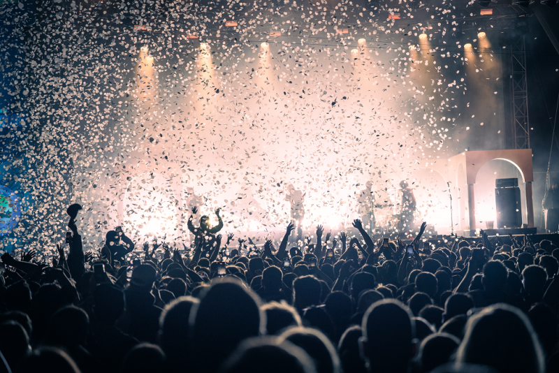 Konzert Publikum jubelt unter Konfetti. Live Musik Festival Stimmung.