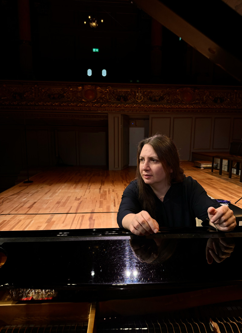 Pianistin am Klavier auf der Bühne. Konzertsaal mit Holzboden im Hintergrund.