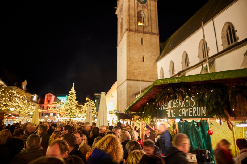 Weihnachtsmarkt Szene: Menschenmenge, Turm, Lichter, Weihnachtsbaum. Stimmungsvolle Atmosphäre.