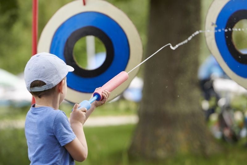 Junge zielt mit Wasserpistole auf Zielscheibe. Sommerspaß im Freien, Wasserspiel für Kinder.