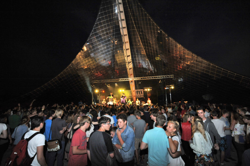Konzert unter Zelt: Band spielt live vor Publikum, das feiert und tanzt. Musikfestival Atmosphäre.