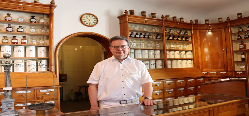 Historische Apotheke: Mann steht vor alten Apothekenschränken mit Arzneiflaschen und -behältern. Nostalgie und Pharmazie.