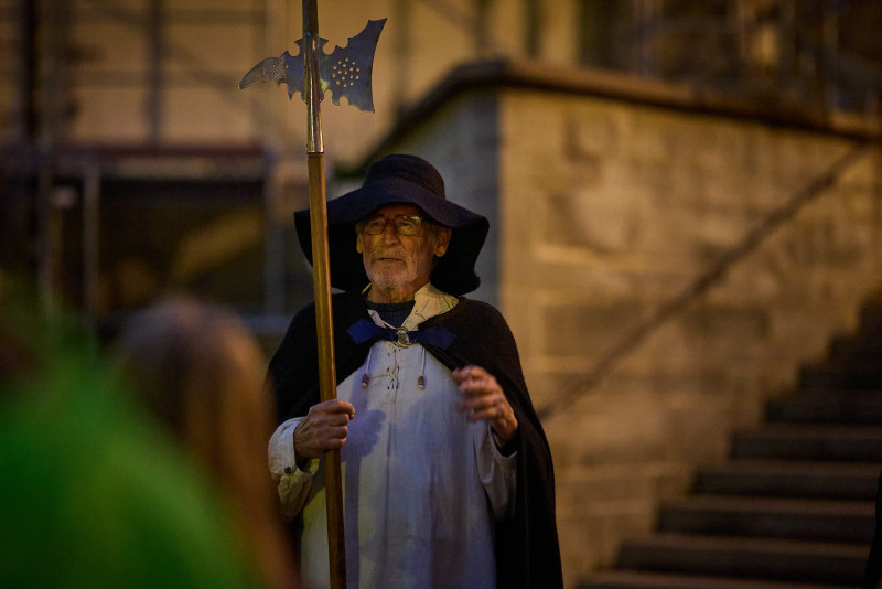 Mittelalterlicher Nachtwächter mit Hellebarde in historischer Tracht bei Nacht. Stadtführung Szene.